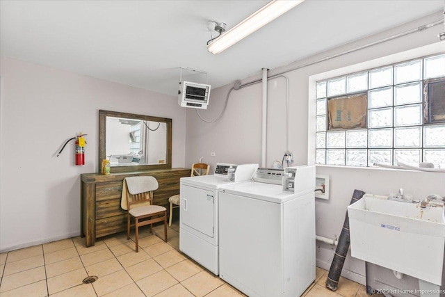 laundry area featuring washer and clothes dryer, a sink, light tile patterned floors, and baseboards