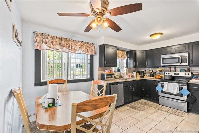 kitchen with stainless steel appliances, a sink, tasteful backsplash, dark cabinets, and light tile patterned floors