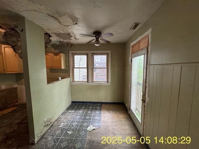 unfurnished dining area featuring wainscoting, a ceiling fan, visible vents, and tile patterned floors