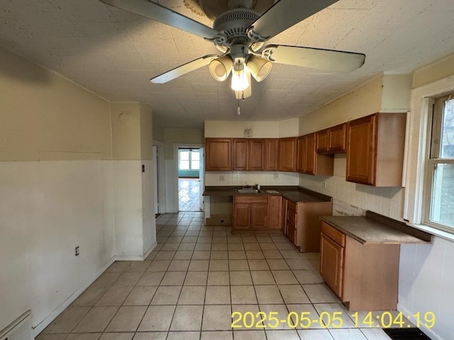 kitchen with dark countertops, a healthy amount of sunlight, ceiling fan, and light tile patterned flooring