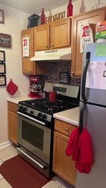 15015 Winchester Ave, Harvey, IL 60426 - kitchen with under cabinet range hood, tasteful backsplash, light tile patterned floors, and appliances with stainless steel finishes