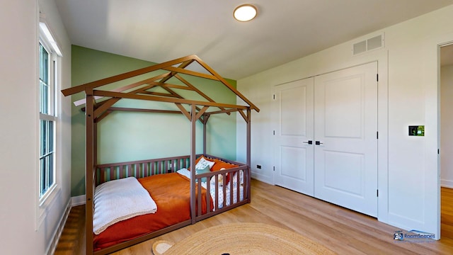 bedroom with wood finished floors, a closet, and baseboards