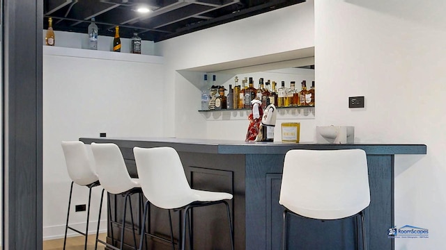 indoor dry bar with wood finished floors and baseboards