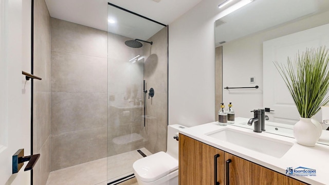 bathroom featuring toilet, a tile shower, and vanity