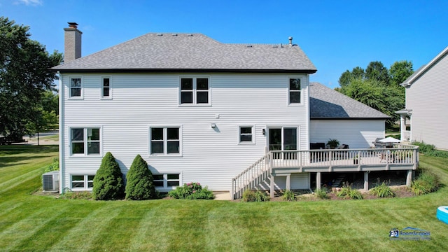rear view of property with a chimney, a wooden deck, roof with shingles, a lawn, and central AC