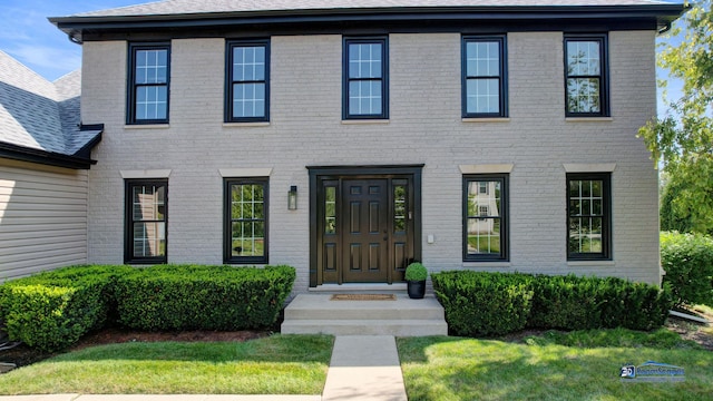 colonial-style house featuring brick siding and a front yard
