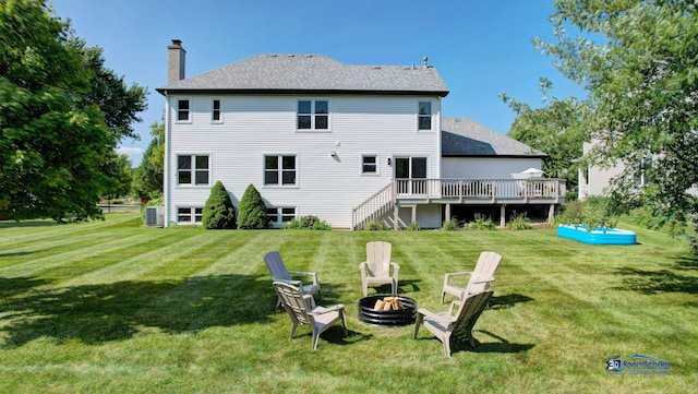 back of property with a fire pit, a chimney, a deck, and a yard