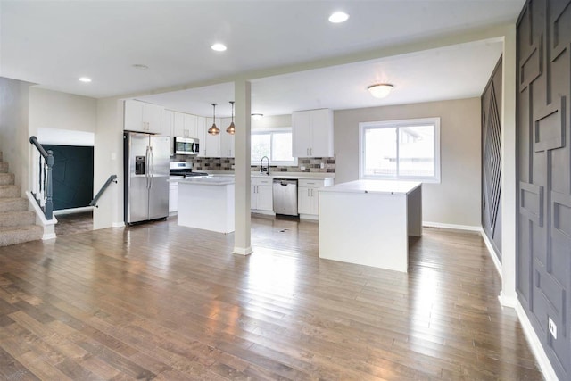 kitchen with appliances with stainless steel finishes, a kitchen island, a sink, light countertops, and recessed lighting