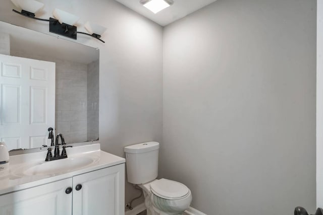 bathroom with toilet, vanity, and baseboards