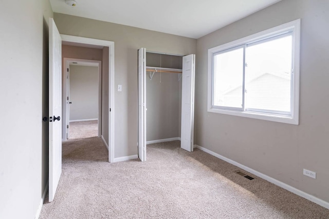 unfurnished bedroom with light colored carpet, baseboards, and a closet