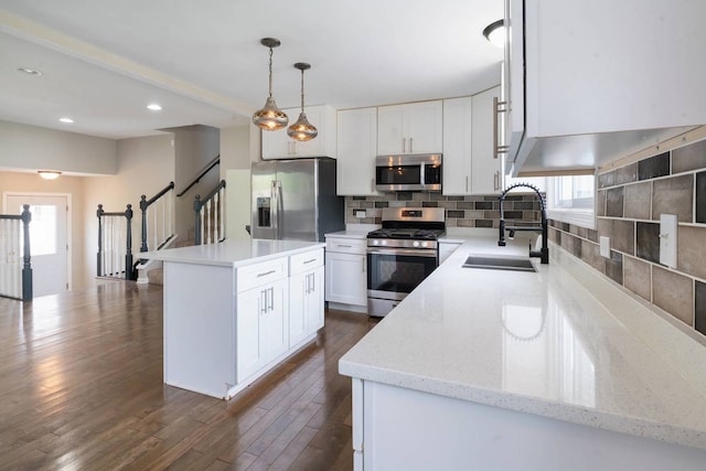 kitchen featuring stainless steel appliances, a sink, decorative backsplash, white cabinetry, and recessed lighting