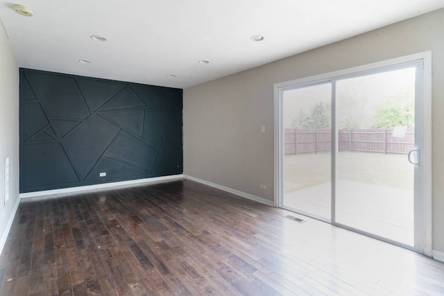 spare room with wood-type flooring, baseboards, recessed lighting, and an accent wall