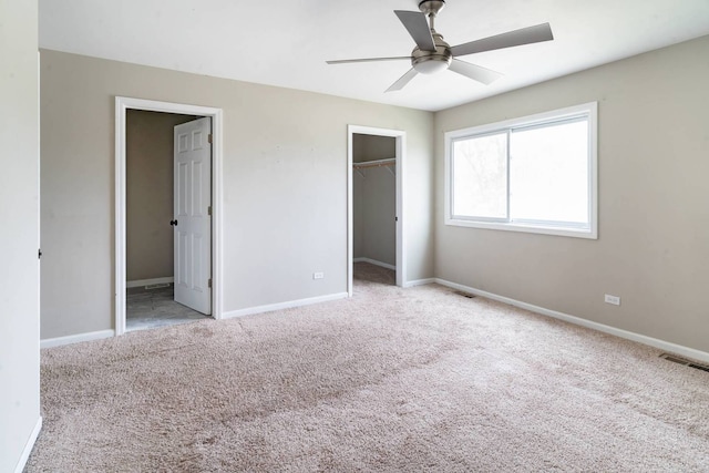 unfurnished bedroom featuring carpet flooring, a spacious closet, and baseboards
