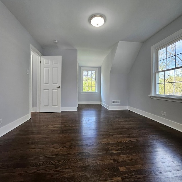 additional living space featuring dark wood-style floors, lofted ceiling, and baseboards