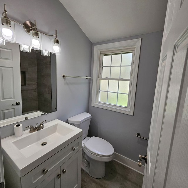 bathroom with toilet, lofted ceiling, and vanity