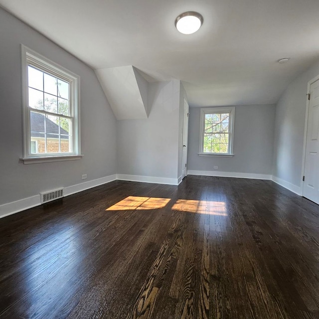 bonus room with lofted ceiling, dark wood-type flooring, and baseboards