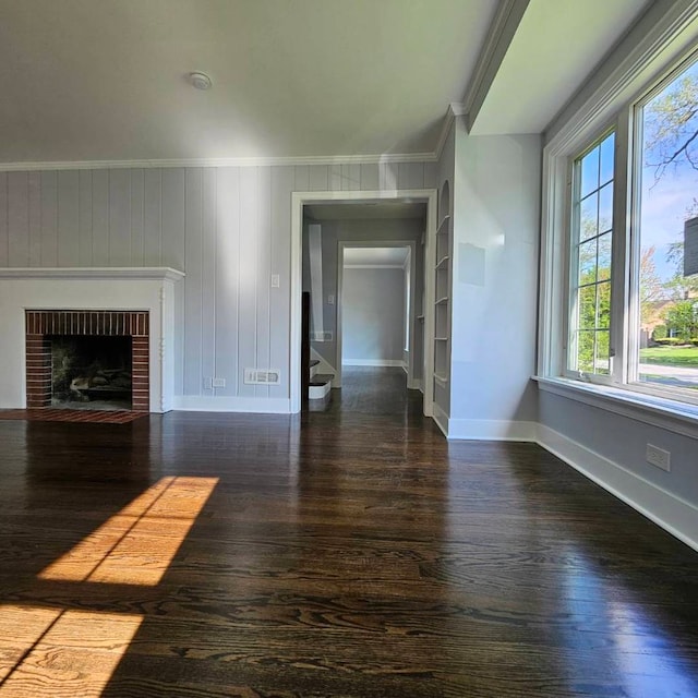 unfurnished living room with ornamental molding, wood finished floors, baseboards, stairway, and a fireplace