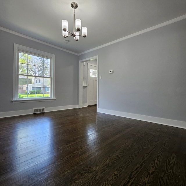 spare room featuring a chandelier, ornamental molding, dark wood-type flooring, and baseboards