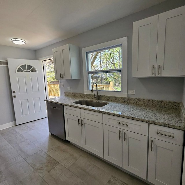 kitchen with a sink, stainless steel dishwasher, light stone counters, and white cabinetry