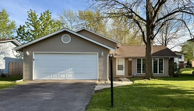 ranch-style house featuring driveway, a garage, and a front lawn