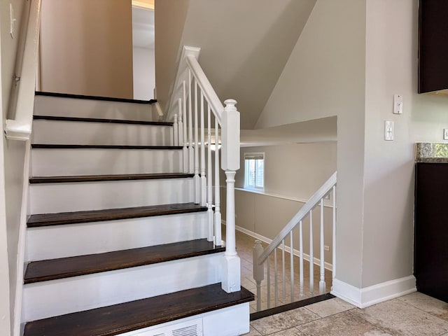 stairs featuring tile patterned flooring, baseboards, and vaulted ceiling