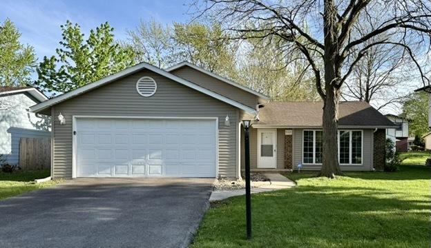 ranch-style house with driveway, an attached garage, and a front yard