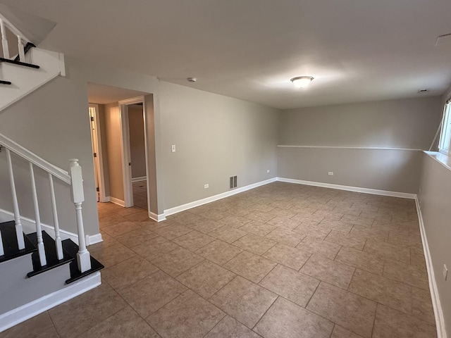 below grade area featuring stairs, baseboards, and tile patterned flooring