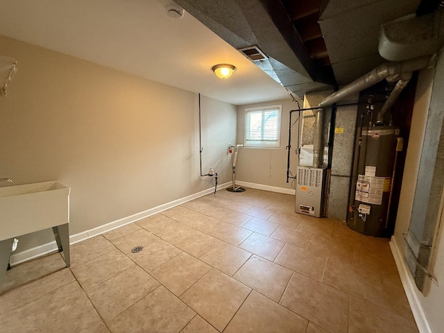 below grade area featuring water heater, baseboards, and light tile patterned floors