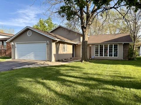 single story home featuring an attached garage, asphalt driveway, a front lawn, and brick siding