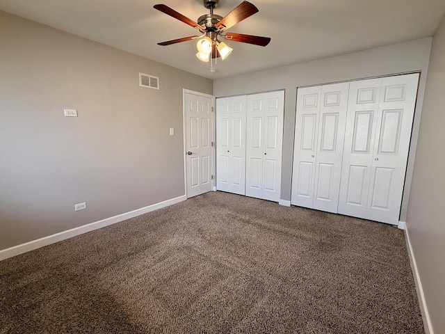 unfurnished bedroom featuring baseboards, two closets, and carpet flooring