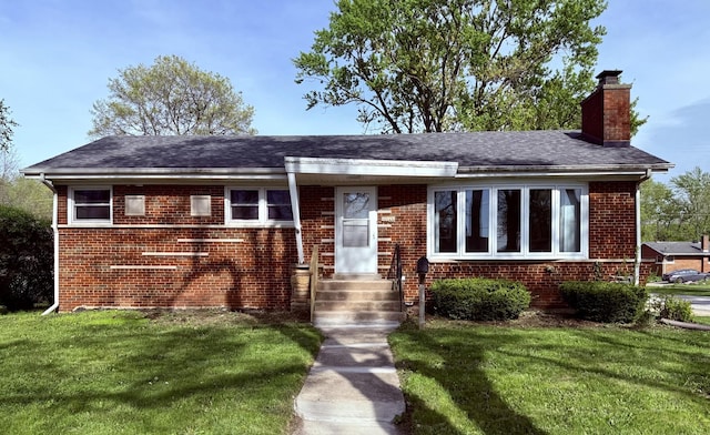 view of front of house featuring a chimney, a front lawn, brick siding, and entry steps
