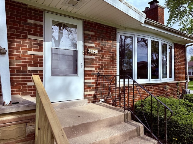 entrance to property featuring brick siding and a chimney