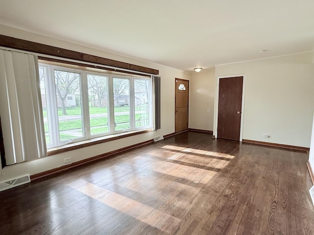 unfurnished living room with dark wood finished floors, crown molding, and baseboards
