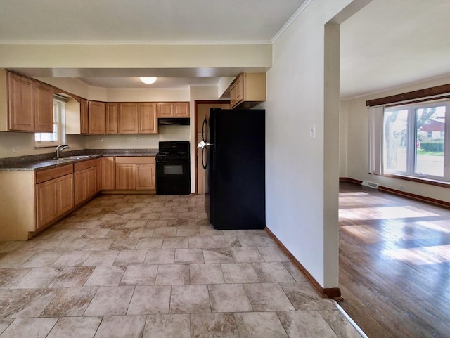 kitchen featuring black appliances, under cabinet range hood, baseboards, dark countertops, and stone finish floors