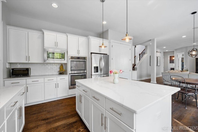 kitchen with stainless steel appliances, backsplash, a center island, dark wood finished floors, and white cabinets