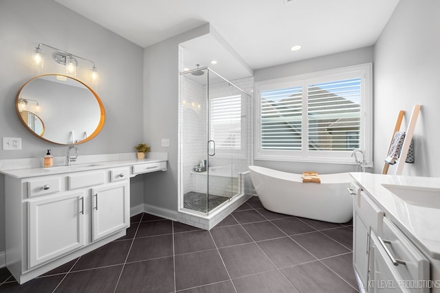 full bath with a stall shower, two vanities, tile patterned flooring, a freestanding bath, and baseboards