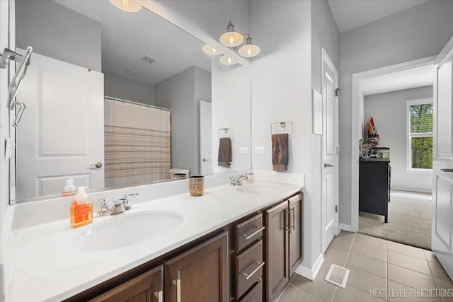 full bathroom featuring tile patterned floors, double vanity, and baseboards