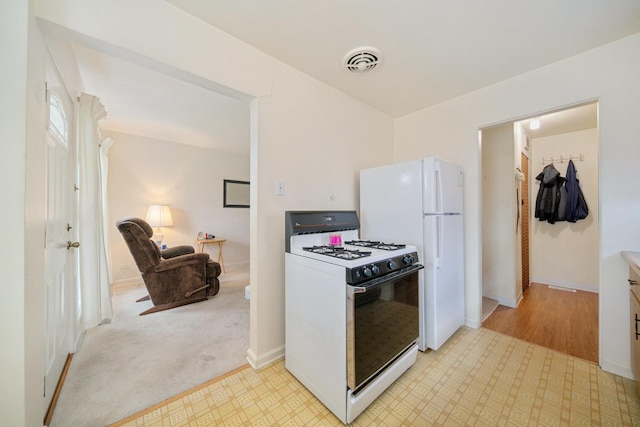 kitchen featuring white appliances, baseboards, and light floors