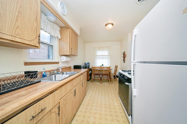 kitchen featuring white appliances, light flooring, light brown cabinetry, a sink, and butcher block countertops