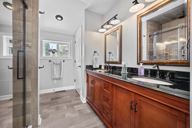 bathroom featuring a stall shower, double vanity, and baseboards