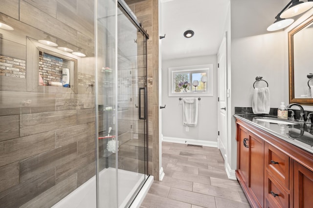 bathroom with a shower stall, baseboards, and vanity