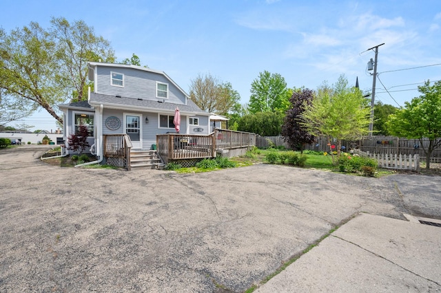 rear view of house featuring fence and a wooden deck