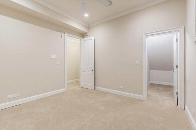 unfurnished bedroom featuring light colored carpet, ornamental molding, baseboards, and a ceiling fan