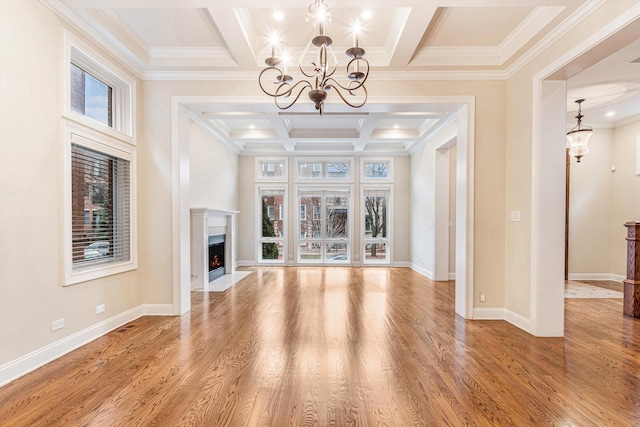 unfurnished living room featuring a chandelier, plenty of natural light, wood finished floors, and coffered ceiling