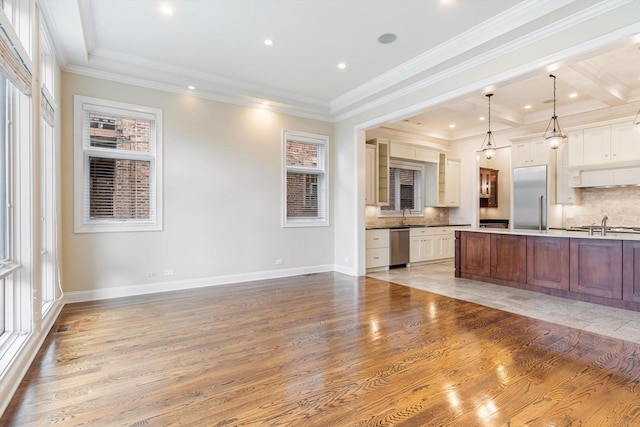 kitchen with appliances with stainless steel finishes, a sink, light wood finished floors, and tasteful backsplash