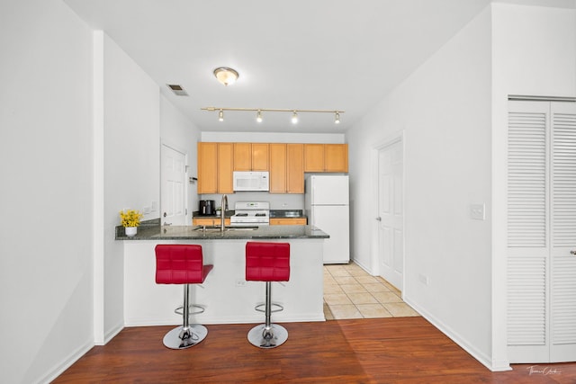 758 W 15th St Unit 3A, Chicago, IL 60607 - kitchen featuring white appliances, visible vents, a sink, a peninsula, and a kitchen breakfast bar