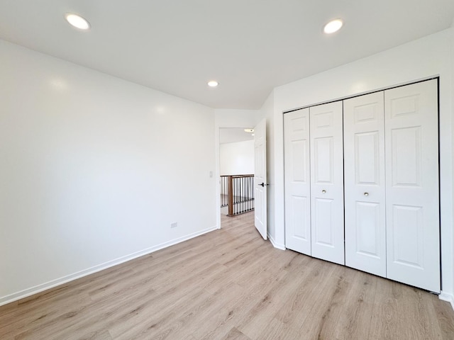 unfurnished bedroom featuring light wood-style floors, baseboards, a closet, and recessed lighting