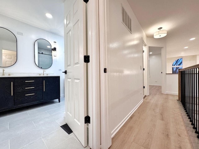 hallway with a sink, recessed lighting, and baseboards