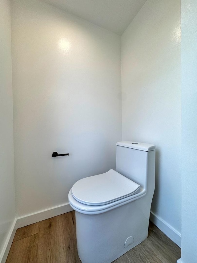 bathroom with baseboards, wood finished floors, and toilet