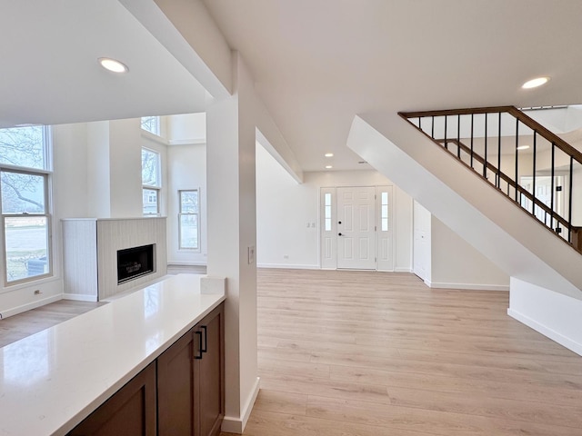unfurnished living room with baseboards, light wood finished floors, stairway, recessed lighting, and a fireplace